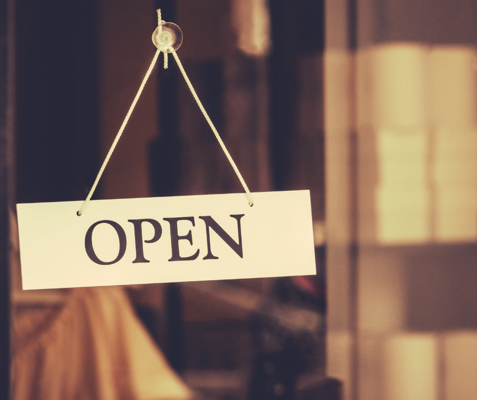 Open sign hanging on glass door of small business