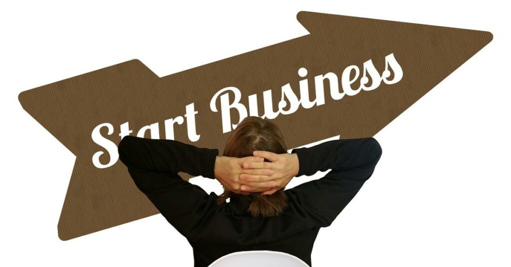 Man in suit leaning back with hands behind head, relaxed. Looking at. arrow that says start business