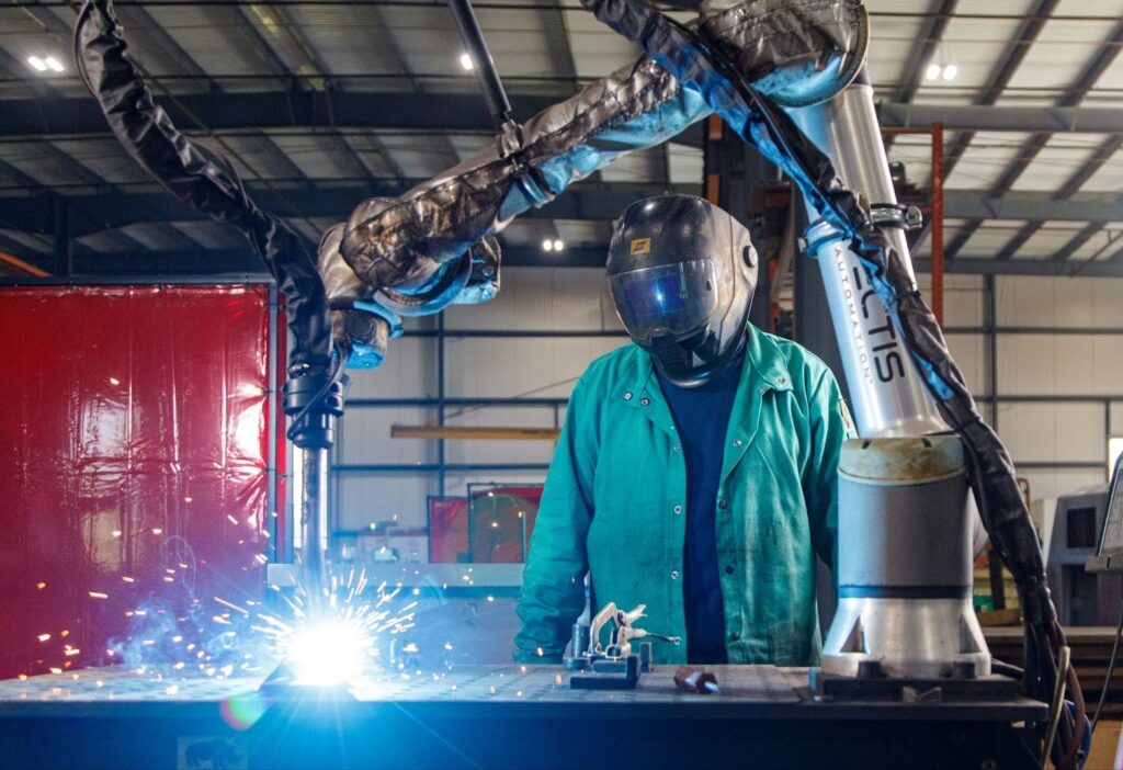worker in a laser fabrication workshop wearing protective gear, including a full-face visor.