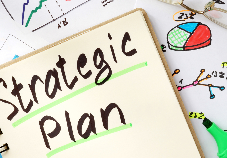 Colorful image of a notebook reading Strategic Plan on top of sketches of different types of charts and graphs