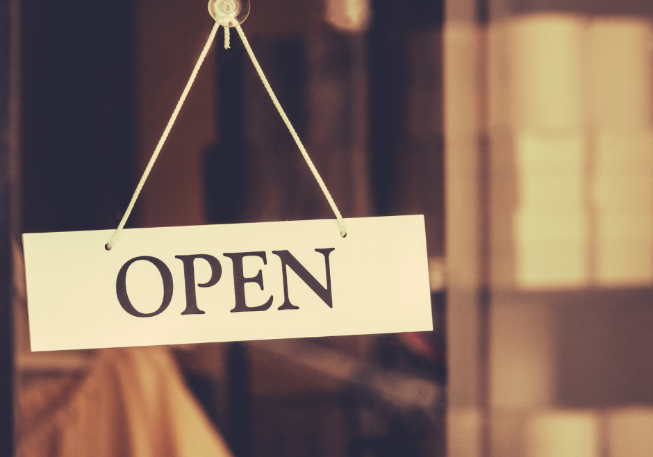 Open sign hanging on glass door of small business