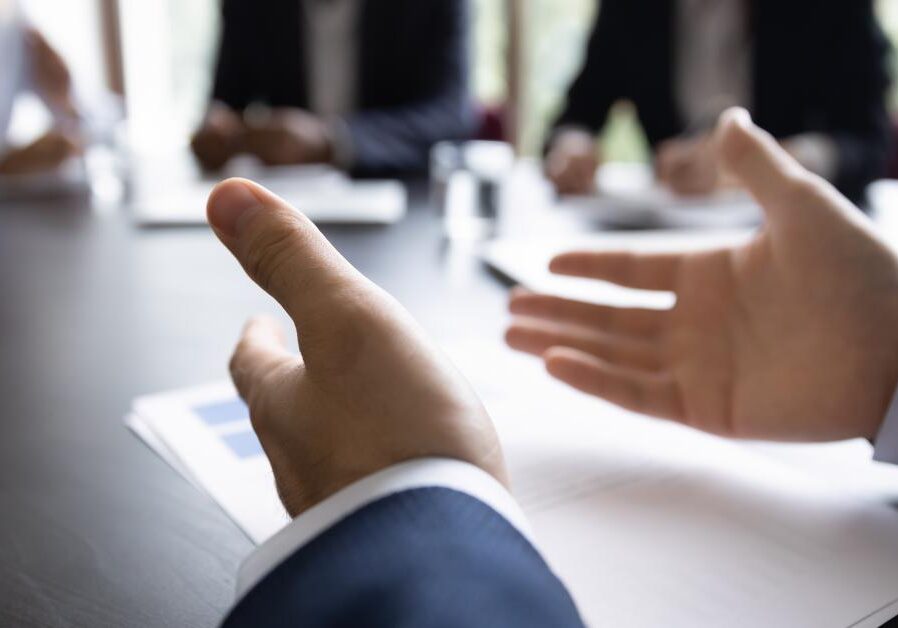 A business coach speaking at a table to others about the qualities of a good business coach