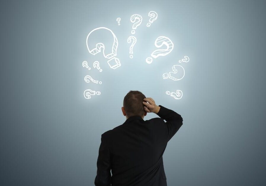 business man staring up at question marks