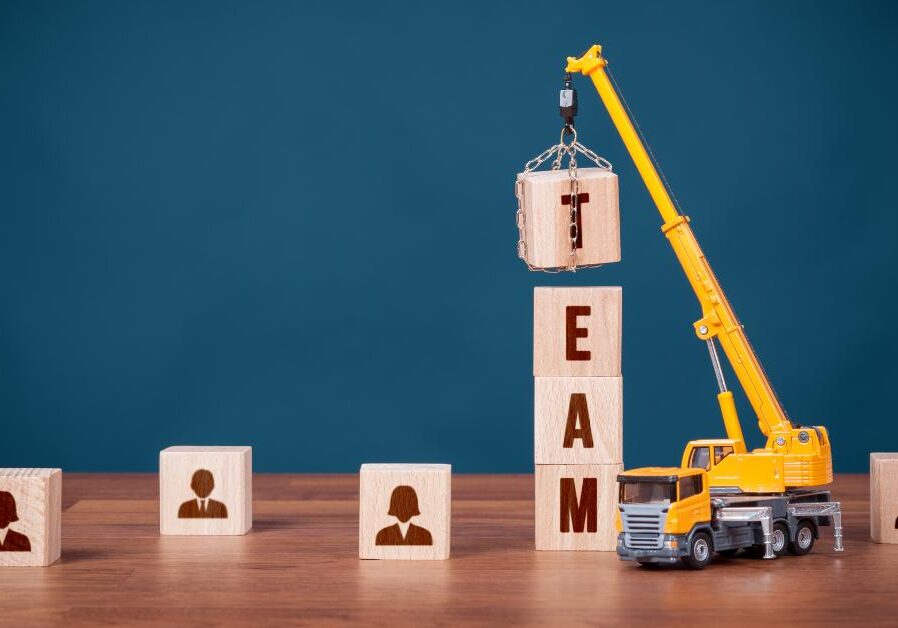 toy crane lifting blocks that spell "team" into place
